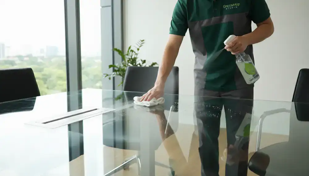 GreenMop Studio professional wiping a glass conference table with eco-friendly spray